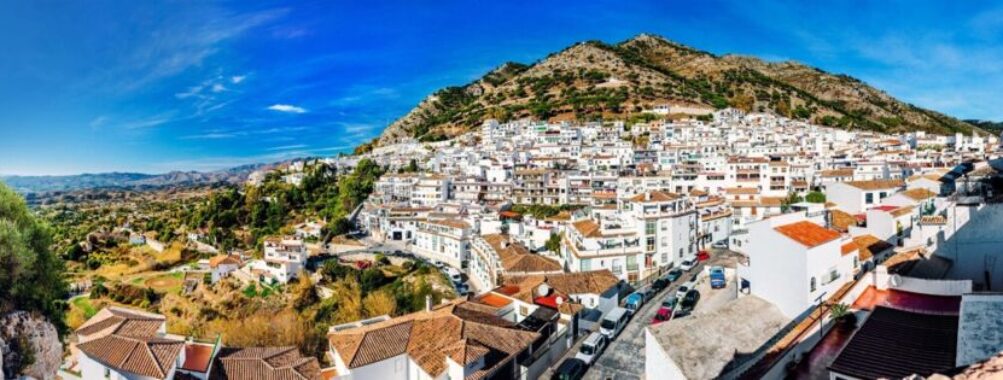 Panoramic view of a whitewashed hillside village with terra cotta roofs in a mountainous region.