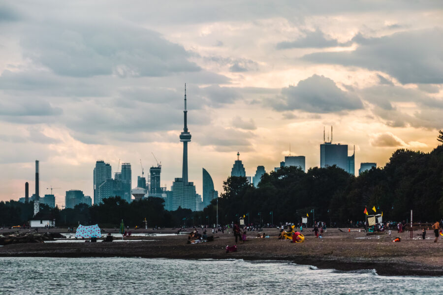 Sunset over Woodbine Beach with the Toronto skyline silhouetted against a vibrant sky, reflecting on the water's surface